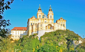 Blick von unten auf das Stift Melk hoch oben auf einem grünen Hügel an einem sonnigen Tag