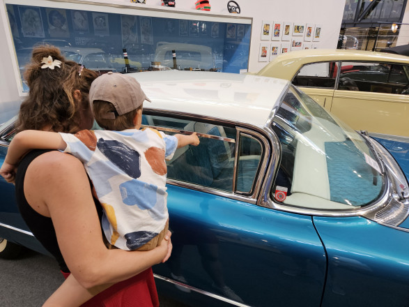 Eine Frau mit einem Jungen am Arm blicken auf einen Oldtimer