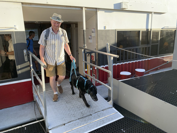Mann mit Hund geht über die Rampe des Schiffs