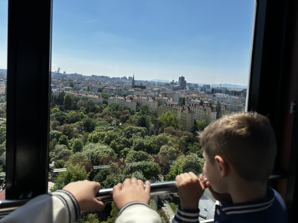 Kind steht an Gondel-Fenster, blickt auf Wien hinab