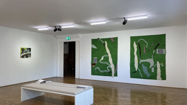 Blick durch den Ausstellungsraum auf große grüne Wandbilder.