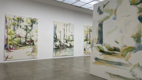 Blick durch den Ausstellungsraum auf grün-weiße Kunst.